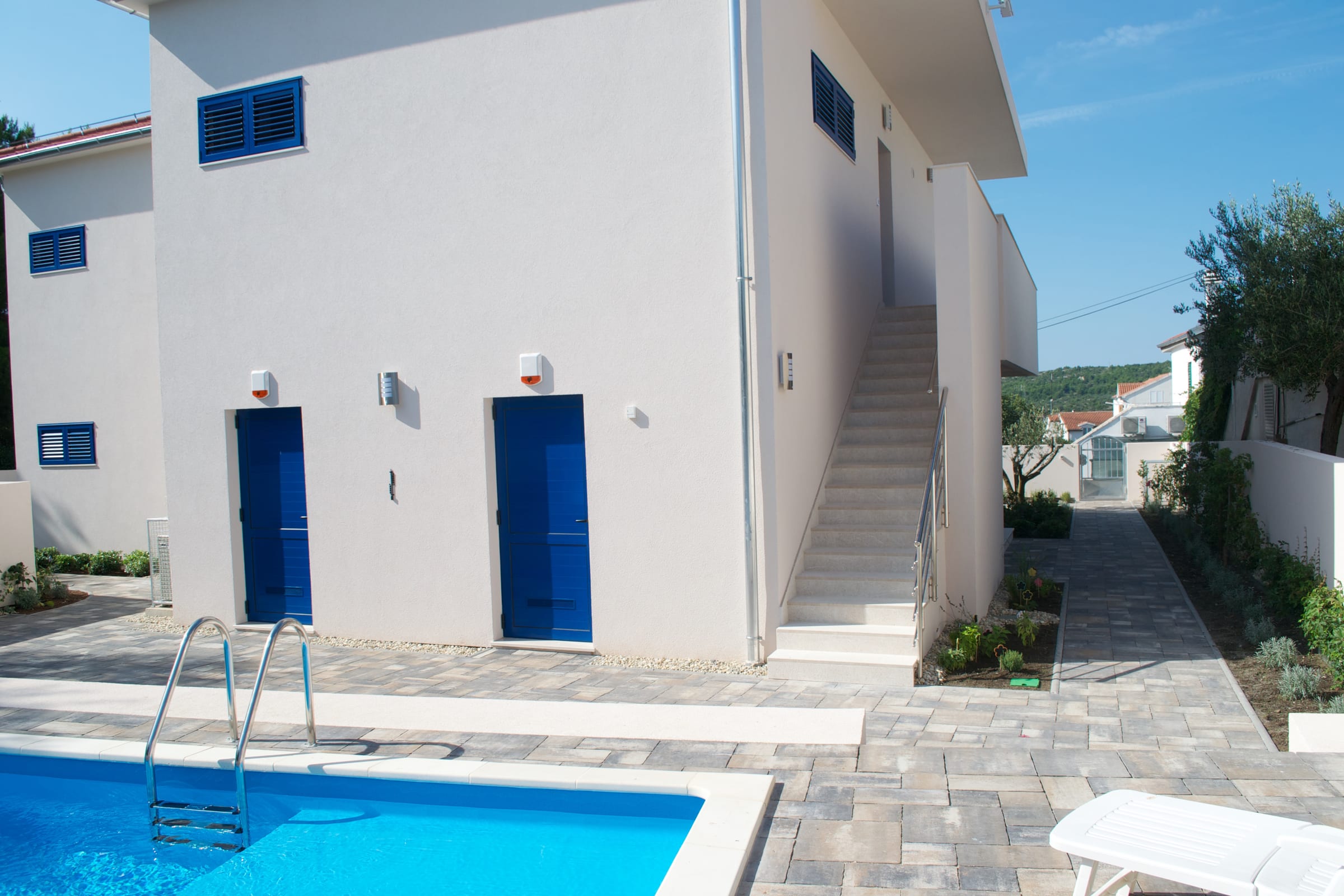 The private pool at Villa LAVA, with the white villa and its blue doors and external stair behind