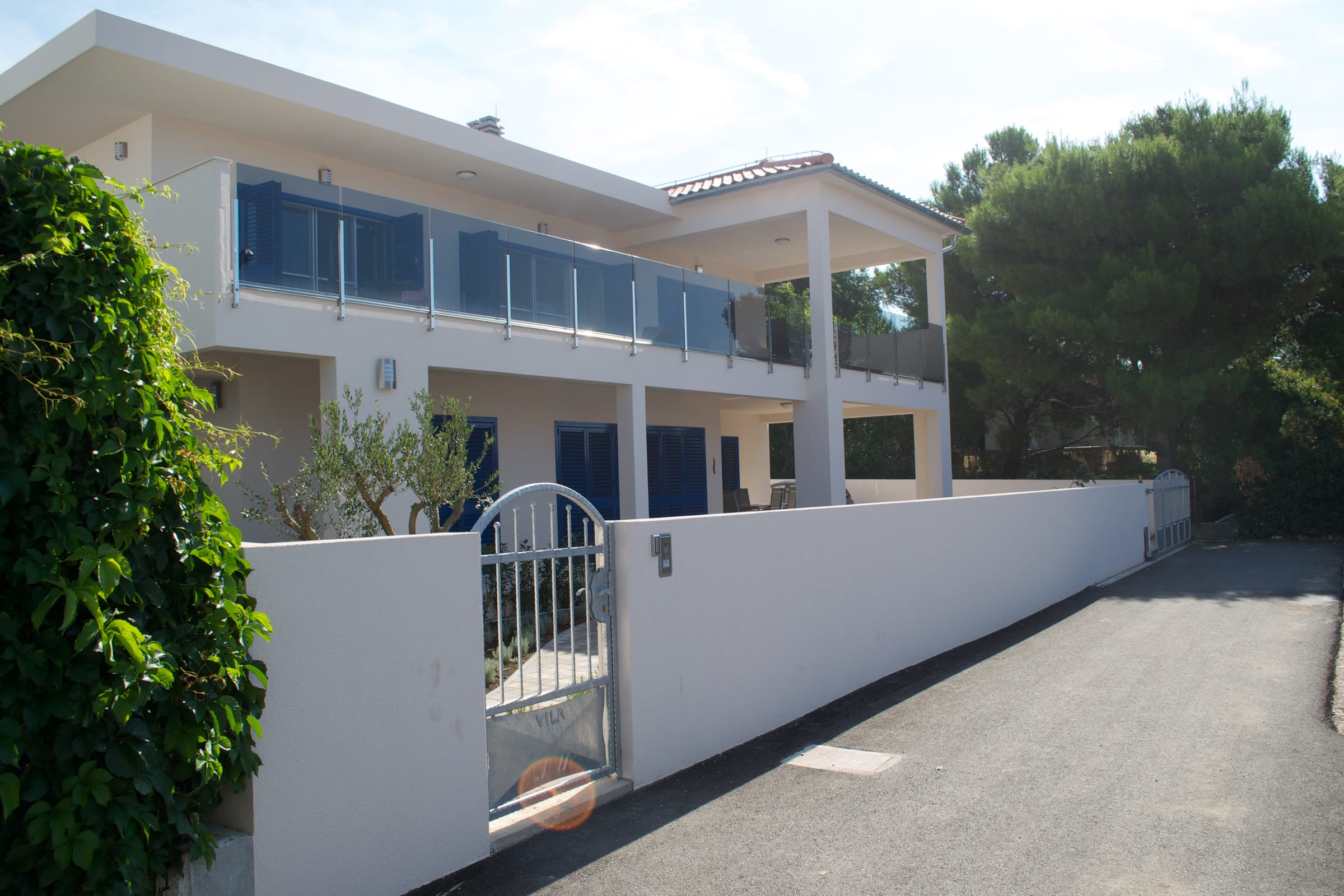 Villa LAVA seen from the driveway, with its gated entrance and the upper terrace’s glass balustrade
